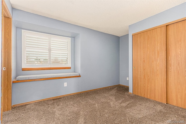 unfurnished bedroom featuring baseboards, a closet, carpet floors, and a textured ceiling