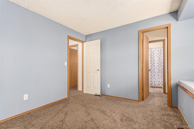 unfurnished bedroom with carpet flooring, a textured ceiling, and baseboards