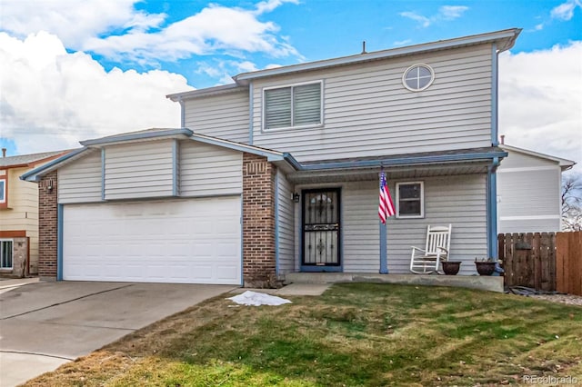 traditional home with a front yard, fence, driveway, a garage, and brick siding