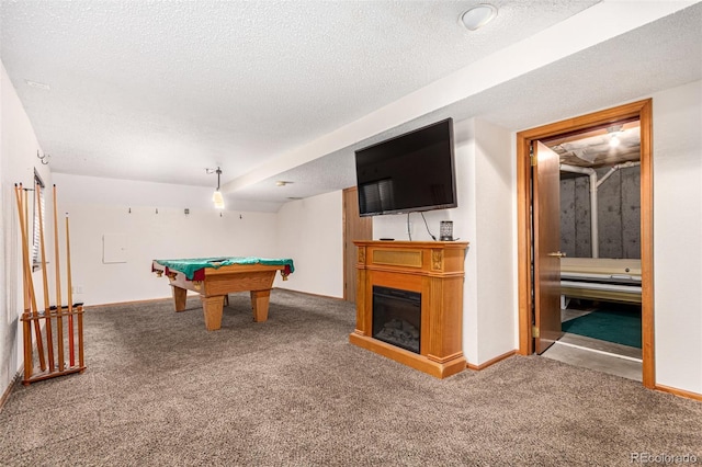 game room featuring baseboards, a textured ceiling, a glass covered fireplace, and carpet flooring