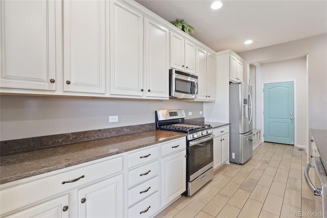 kitchen with baseboards, dark stone counters, recessed lighting, appliances with stainless steel finishes, and white cabinetry