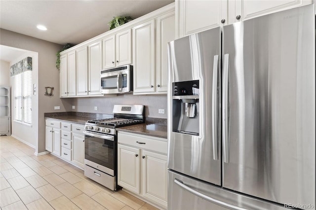 kitchen with dark countertops, white cabinetry, recessed lighting, appliances with stainless steel finishes, and light tile patterned flooring