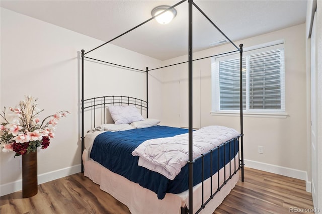 bedroom with wood finished floors, visible vents, and baseboards