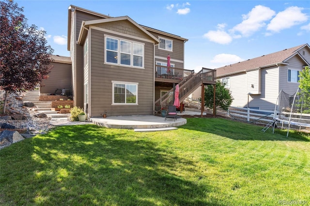 back of house featuring a patio, a trampoline, fence, a yard, and stairs