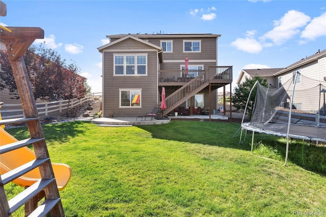 rear view of property with a trampoline, a lawn, stairs, and a patio area