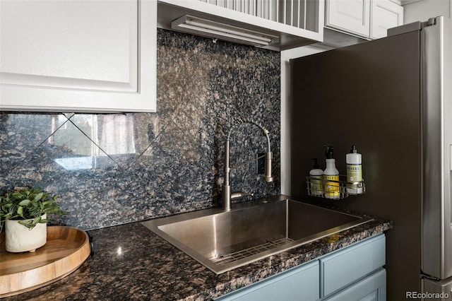 601 W 11th Ave Unit 910, Denver, CO 80204 - kitchen with a sink, freestanding refrigerator, decorative backsplash, white cabinetry, and dark stone countertops