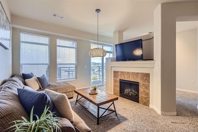 carpeted living area featuring a tile fireplace, visible vents, and baseboards