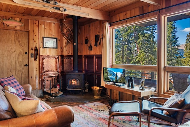 living room featuring wood ceiling, wooden walls, and a wood stove