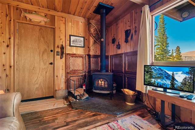 living room featuring wooden ceiling, wooden walls, a wood stove, and hardwood / wood-style flooring