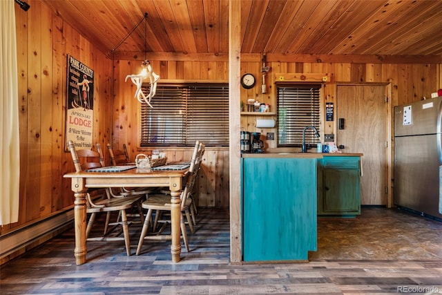 kitchen with wood ceiling, stainless steel fridge, wood walls, and pendant lighting