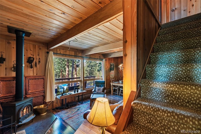 interior space featuring wood ceiling, beam ceiling, and a wood stove