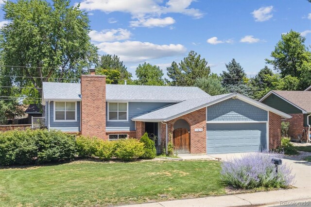 11815 E Louisiana Ave, Aurora, CO 80012 - view of front of property with an attached garage, a front lawn, a chimney, brick siding, and concrete driveway
