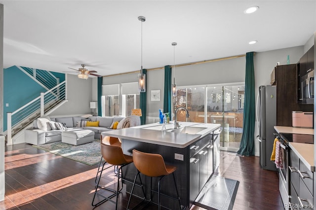 kitchen with stainless steel appliances, an island with sink, a healthy amount of sunlight, and dark hardwood / wood-style flooring