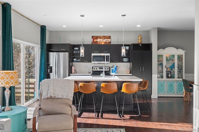 kitchen featuring stainless steel appliances, dark hardwood / wood-style floors, a kitchen bar, and hanging light fixtures