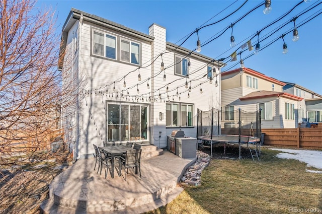 back of property featuring a trampoline, a yard, and a patio area