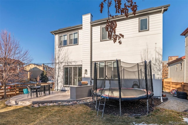 back of house with a yard, a patio area, and a trampoline