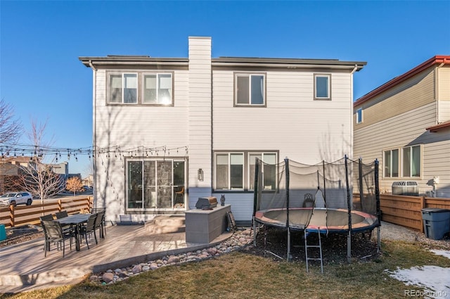 rear view of house featuring a patio, a yard, and a trampoline