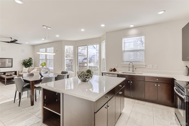 kitchen with dark brown cabinetry, range with electric cooktop, a kitchen island, light countertops, and a sink