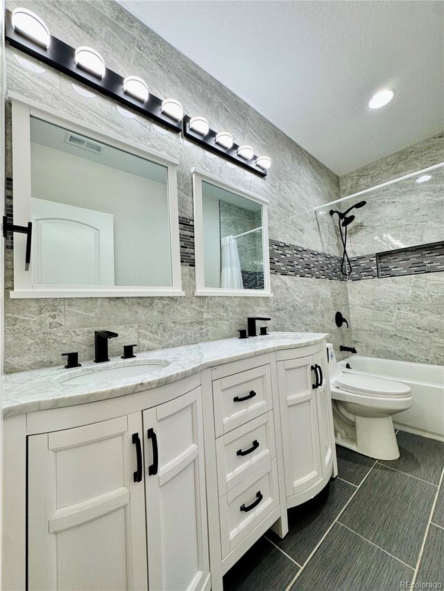 full bath with tile walls, double vanity, shower / bath combination with curtain, visible vents, and a sink