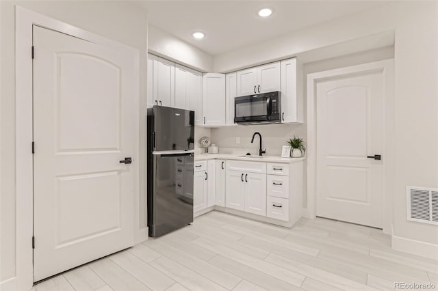 kitchen with recessed lighting, visible vents, white cabinetry, light countertops, and black appliances