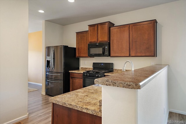 kitchen with black appliances, baseboards, light wood-style floors, a peninsula, and recessed lighting