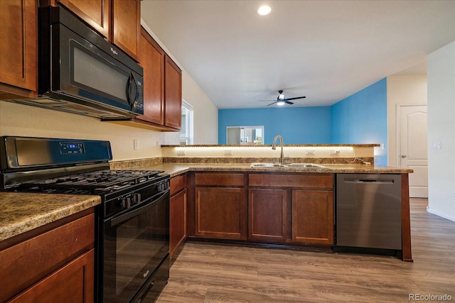 kitchen featuring black appliances, a sink, a ceiling fan, wood finished floors, and a peninsula
