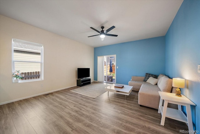 living area featuring plenty of natural light, ceiling fan, wood finished floors, and baseboards