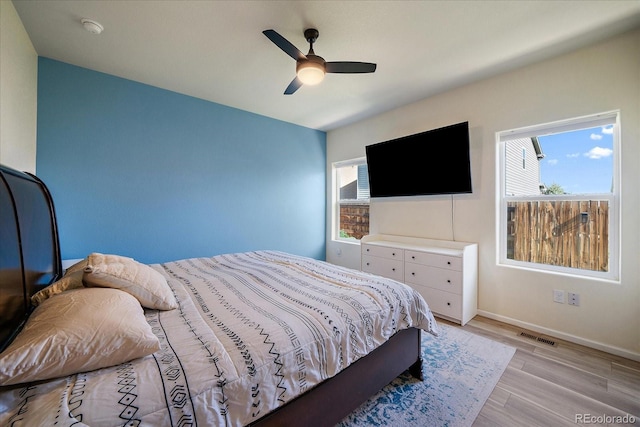 bedroom featuring multiple windows, light wood-style flooring, baseboards, and a ceiling fan