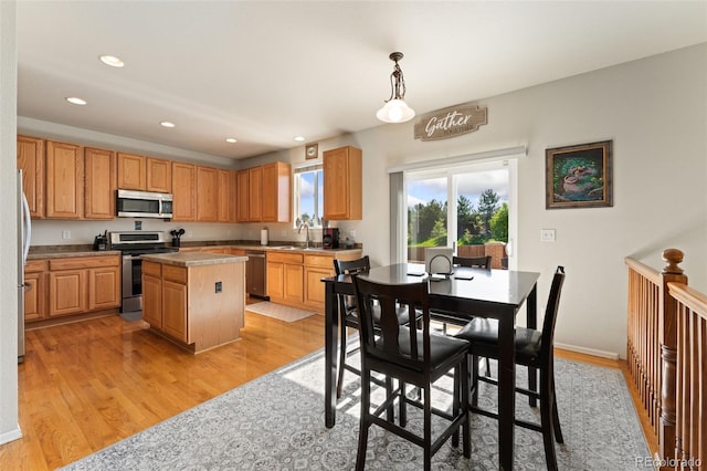 12978 Newport Way, Thornton, CO 80602 - kitchen with stainless steel appliances, a center island, light wood-style floors, recessed lighting, and hanging light fixtures