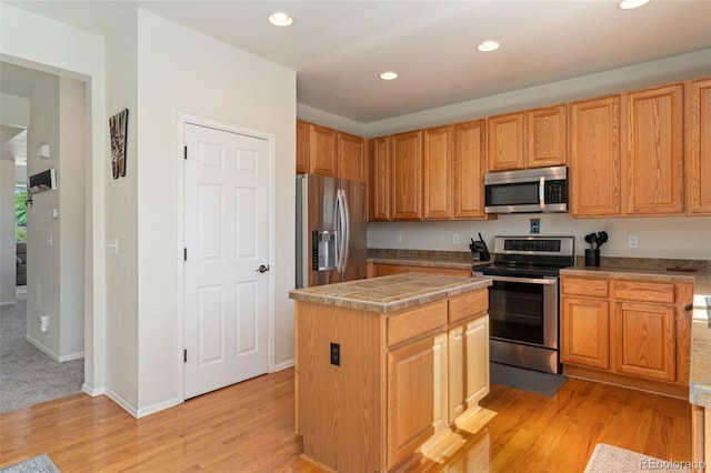 12978 Newport Way, Thornton, CO 80602 - kitchen featuring stainless steel appliances, light wood-style flooring, recessed lighting, a kitchen island, and tile counters