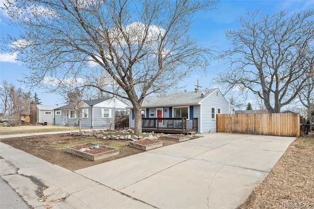 single story home featuring a garden, a residential view, fence, and concrete driveway