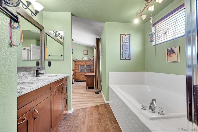 full bathroom with a garden tub, wood finished floors, vanity, and baseboards