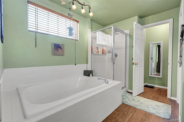 full bathroom featuring a garden tub, baseboards, wood finished floors, and a shower stall