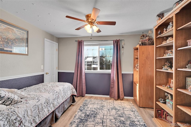 bedroom featuring a textured ceiling, ceiling fan, and light wood finished floors