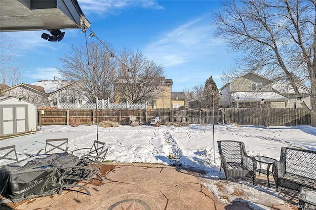 yard covered in snow featuring an outbuilding, a shed, and a fenced backyard