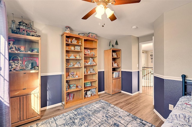 sitting room with a ceiling fan, baseboards, light wood finished floors, and an upstairs landing