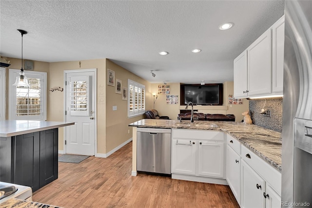 14558 Vine St, Thornton, CO 80602 - kitchen featuring appliances with stainless steel finishes, a peninsula, recessed lighting, plenty of natural light, and white cabinetry