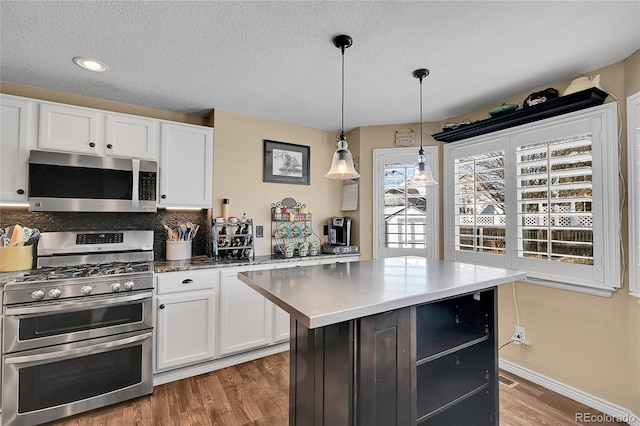 14558 Vine St, Thornton, CO 80602 - kitchen featuring stainless steel appliances, wood finished floors, white cabinets, hanging light fixtures, and a textured ceiling