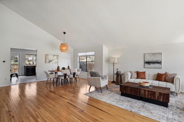 living room with baseboards, high vaulted ceiling, hardwood / wood-style floors, and a wealth of natural light