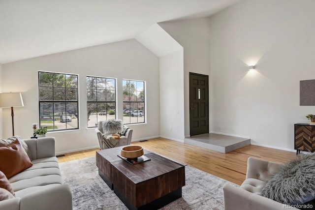 living room with high vaulted ceiling, baseboards, and wood finished floors
