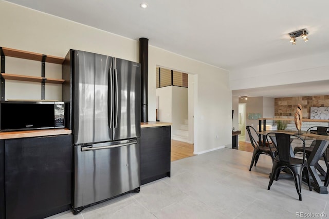kitchen featuring dark cabinetry, freestanding refrigerator, open shelves, and light tile patterned flooring