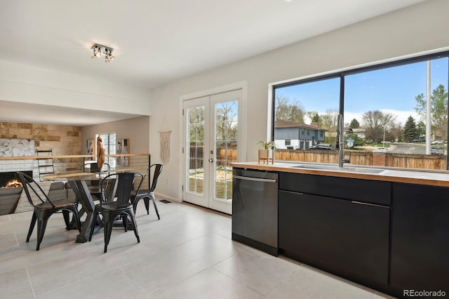 dining room featuring french doors, light tile patterned flooring, and a warm lit fireplace