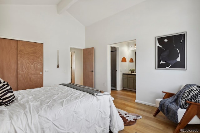 bedroom featuring beam ceiling, high vaulted ceiling, baseboards, connected bathroom, and light wood-style flooring