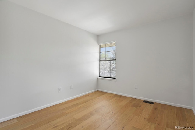 unfurnished room with baseboards, light wood-style floors, and visible vents