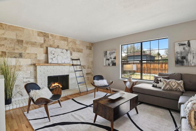 living area with baseboards, wood finished floors, and a fireplace