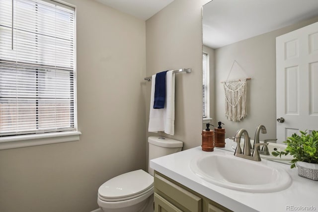 bathroom with toilet, a wealth of natural light, and vanity