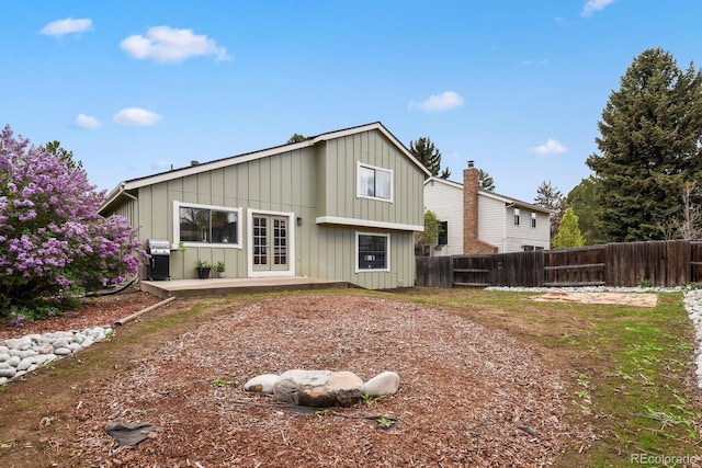 back of property featuring board and batten siding, fence, and french doors