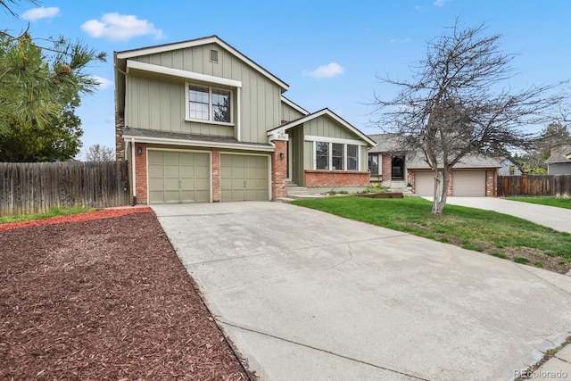 tri-level home featuring board and batten siding, brick siding, fence, a front lawn, and concrete driveway