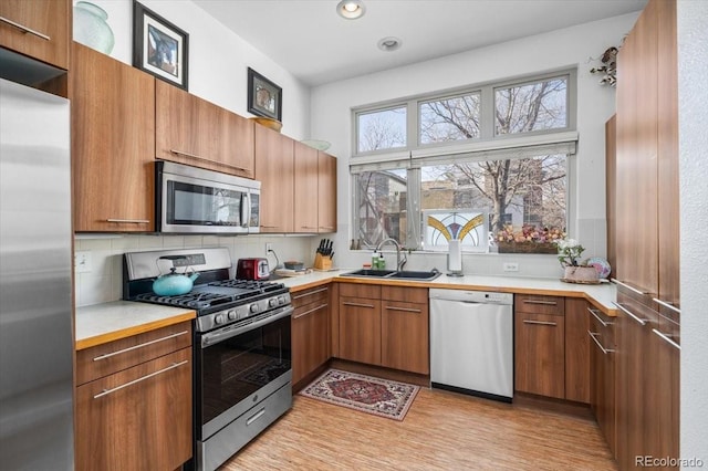 kitchen featuring sink, backsplash, light hardwood / wood-style flooring, and stainless steel appliances