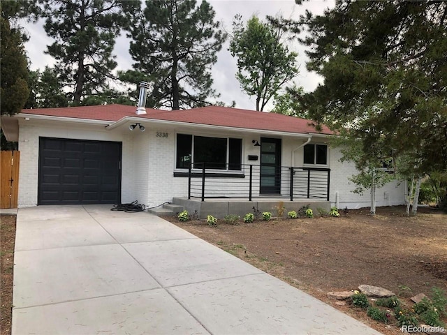 single story home featuring a garage, driveway, brick siding, and covered porch